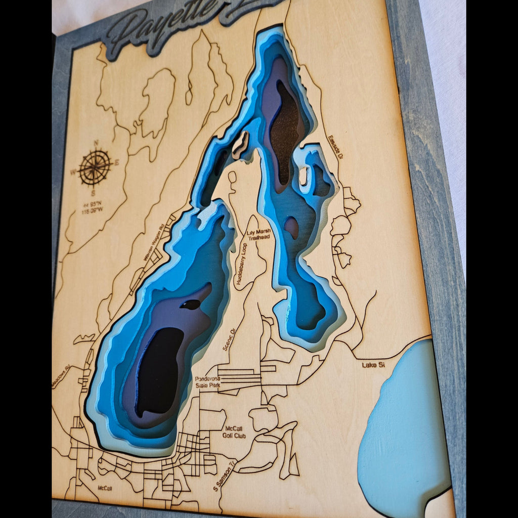 Wooden map with laser-cut topography of a lake, featuring blue for water and brown for land.